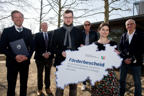 Staatssekretär Dr. Dirk Günnewig (l.) überreichte Dr. Elisabeth Kreidt und Dr. Sidney Becker (vorne) die Förderbescheide im Beisein von (v.l.) Prof. Guido Clever, Prodekan der Fakultät für Chemie und Chemische Biologie, Kanzler Albrecht Ehlers und Rektor Prof. Manfred Bayer.